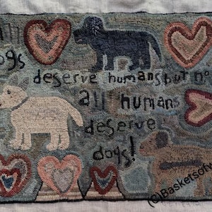 May include: A rectangular hooked rug featuring a blue-grey background with three dogs in black, cream, and brown. The rug displays five hearts and the text: All dogs deserve humans but not all humans deserve dogs! The text Baskets of wool is visible.