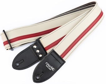 May include: White guitar strap with red stripes and black leather ends. The strap is stitched with white thread and has the text "couch" in black lettering on one end.