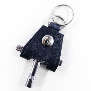 May include: A black leather keychain with a silver tool attached. The tool has a small, round button with a logo on it.
