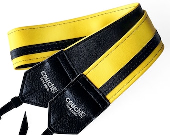 May include: Yellow and black camera strap with black leather ends. The strap has the text "couchilu hand made" on each end.