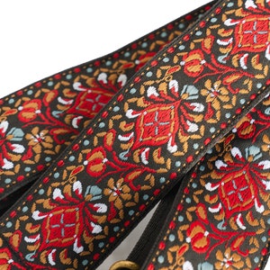May include: Two guitar straps with a black background and a colourful floral pattern in red, orange, white, and blue.