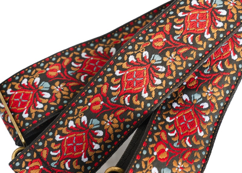 May include: Two guitar straps with a black background and a colourful floral pattern in red, orange, white, and blue.