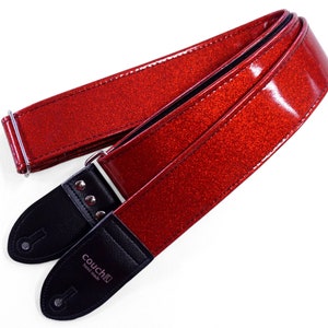 Pu&ograve; includere: Cinturino per chitarra rosso glitterato con estremit&agrave; in pelle nera e accessori argentati. Il cinturino &egrave; realizzato da Couch Guitars e riporta la scritta "Couch Guitars Handmade" sull'estremit&agrave;.