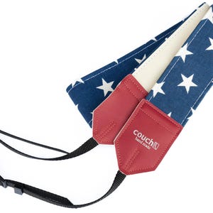 May include: A camera strap with a blue and white star pattern, red leather ends, and black adjustable straps. The red leather ends have the text "couch hand made".
