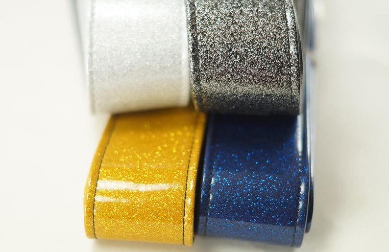 Pu&ograve; includere: Quattro rotoli di nastro glitterato in argento, oro, bianco e blu.