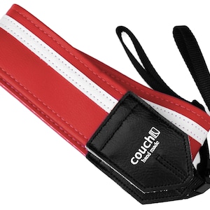May include: Red and white camera strap with a black leather patch that says "couch" and "hand made".
