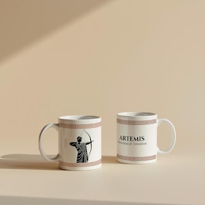May include: Two white ceramic mugs with a brown geometric border. One mug features a black illustration of a figure with a bow and arrow. The other mug has the word "ARTEMIS" and the words "Freedom & Intuition" in black text.