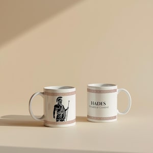 以下が含まれることがあります： 茶色のギリシャキーの縁取りが付いた2つの白いセラミックマグ。1つのマグにはギリシャの人物の黒いイラストが描かれており、もう1つのマグには黒で「HADES Wealth & Control」というテキストが書かれています。