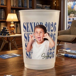 Pode incluir: Um copo de pl&aacute;stico fosco com o texto "SENIOR 2026" em azul marinho. Uma foto de uma menina mostrando a l&iacute;ngua est&aacute; no copo. O nome "Sophia" est&aacute; escrito em it&aacute;lico abaixo.