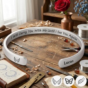 May include: A silver cuff bracelet engraved with "I Will Carry You With Me Until I See You Again" and the name "Lucas." The bracelet features wing and feather designs. A red rose and tools are in the background.