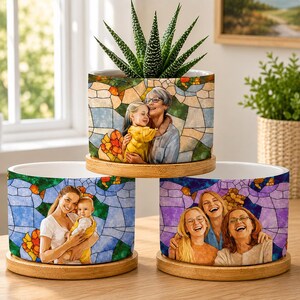 May include: Three cylindrical ceramic planters with wooden bases, each featuring a colorful stained glass pattern background. The planters display printed portraits of family members, including a child with an adult and a group of three women.
