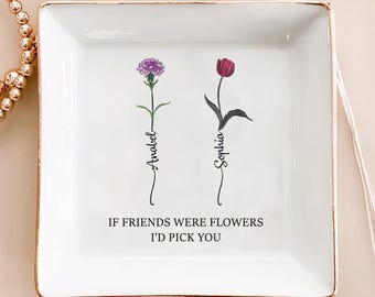 May include: A white square ceramic trinket dish with a gold rim. It features two floral illustrations, one purple and one red, with the names "Anabel" and "Sophia" written below. The text "IF FRIENDS WERE FLOWERS I'D PICK YOU" is also present.
