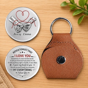 May include: Two circular silver-toned metal discs and a brown leather keychain holder. One disc features two silver hands joined by a red string heart and the names Henry and Emma. The other disc displays the text Never Forget That I Love You.