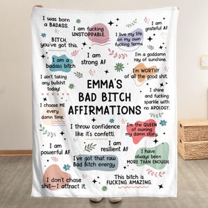 May include: White throw blanket with the text "EMMA'S BAD BITCH AFFIRMATIONS" in black. The blanket features various affirmations in different fonts and colors, with decorative stars and floral elements.