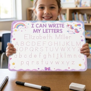 Könnte beinhalten: Ein rechteckiges weißes Whiteboard mit violettem Wellenrand, das den Text I CAN WRITE MY LETTERS, ein Einhorn, einen Regenbogen sowie gepunktete Linien zum Nachspuren des Namens Elizabeth Miller und des gesamten Alphabets in Groß- und Kleinbuchstaben zeigt.