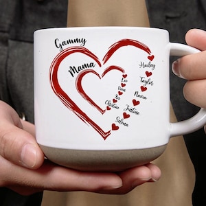 Könnte beinhalten: Weißer Keramikbecher mit grauem Boden, mit einem roten Herzdesign mit den Worten "Gammy" und "Mama". Namen wie Hailey, Taylor und andere sind im Herzen aufgeführt. Ein perfektes Geschenk für die Familie.
