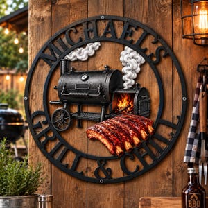 May include: A circular black metal wall sign featuring the text "MICHAEL'S GRILL & CHILL" surrounding a central graphic of a black smoker grill with white smoke plumes and a rack of cooked ribs with visible flames inside the firebox.