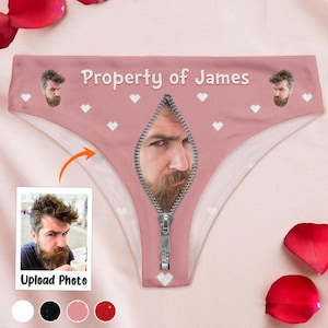 May include: Pink underwear with a zipper design and the text "Property of James". The underwear features a photo of a man's face inside the zipper and small white hearts. A photo with the text "Upload Photo" is in the lower left.