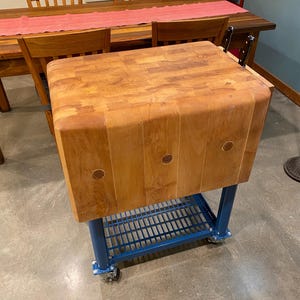 Handgerestaureerd vintage slagersblok met op maat gemaakte metalen basis met poedercoating, wielen en plank. Geschuurd en verzegeld met slagerblokolie.