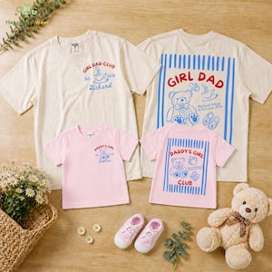 May include: A collection of matching t-shirts in cream and pink, featuring the text "GIRL DAD CLUB" and "DADDY'S GIRL" with teddy bear graphics. Includes pink sneakers and a teddy bear.