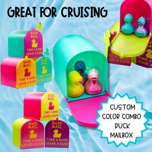 May include: A collection of colorful plastic mailboxes with the text DUCK MAIL TAKE A DUCK LEAVE A DUCK. The mailboxes are pink, yellow, teal, and purple, each containing small rubber ducks. The text GREAT FOR CRUISING and CUSTOM COLOR COMBO DUCK MAILBOX is visible.