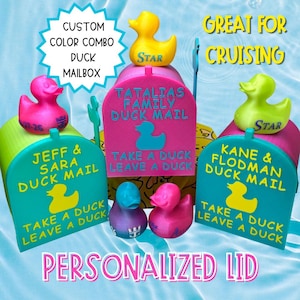 May include: Three 3D-printed plastic mailboxes in pink and teal, each topped with a rubber duck. The mailboxes feature yellow text reading JEFF & SARA DUCK MAIL, TATALIAS FAMILY DUCK MAIL, and KANE & FLODMAN DUCK MAIL, with the phrase TAKE A DUCK LEAVE A DUCK.