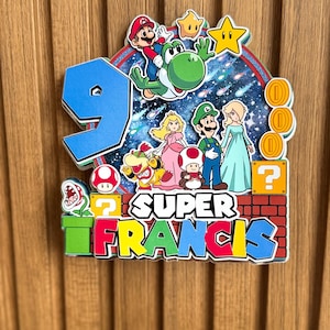 Peut inclure: Un décor de gâteau coloré sur le thème de Super Mario, avec le chiffre 9 en bleu et des personnages comme Mario, Yoshi et la Princesse Peach. Le texte "SUPER FRANCIS" est affiché sur un fond de briques.