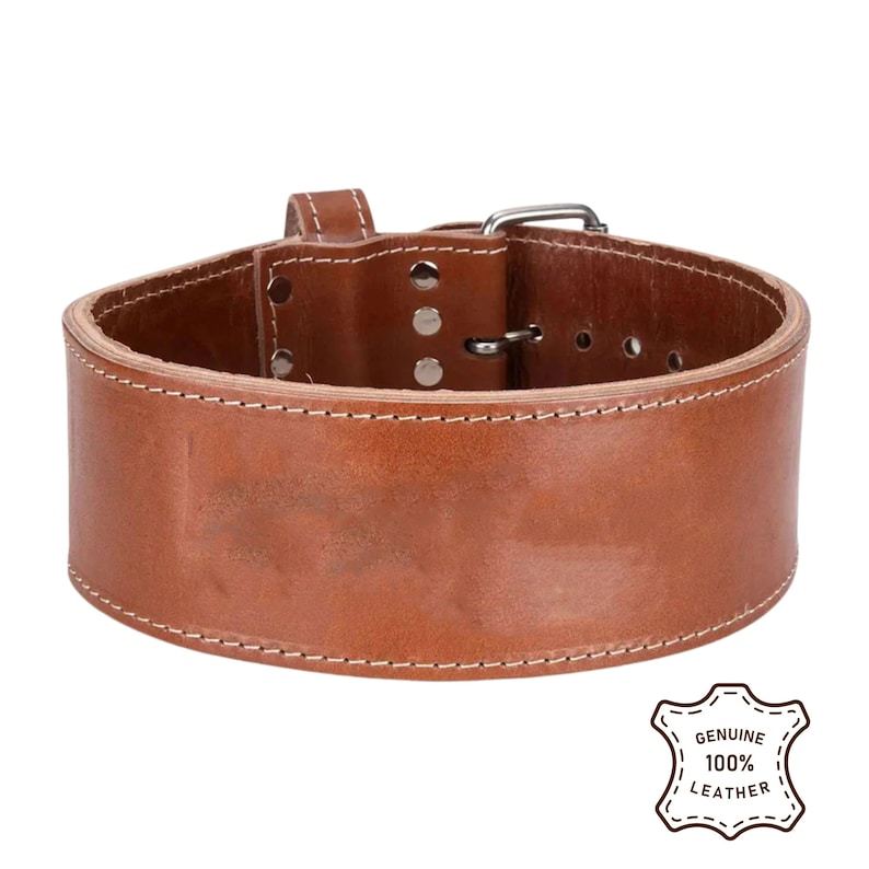 Peut inclure: Une ceinture d'halt&eacute;rophilie en cuir marron avec des coutures blanches. La ceinture est dot&eacute;e d'une fermeture &agrave; boucle et de plusieurs trous de r&eacute;glage. L'image comprend un logo "GENUINE 100% LEATHER".