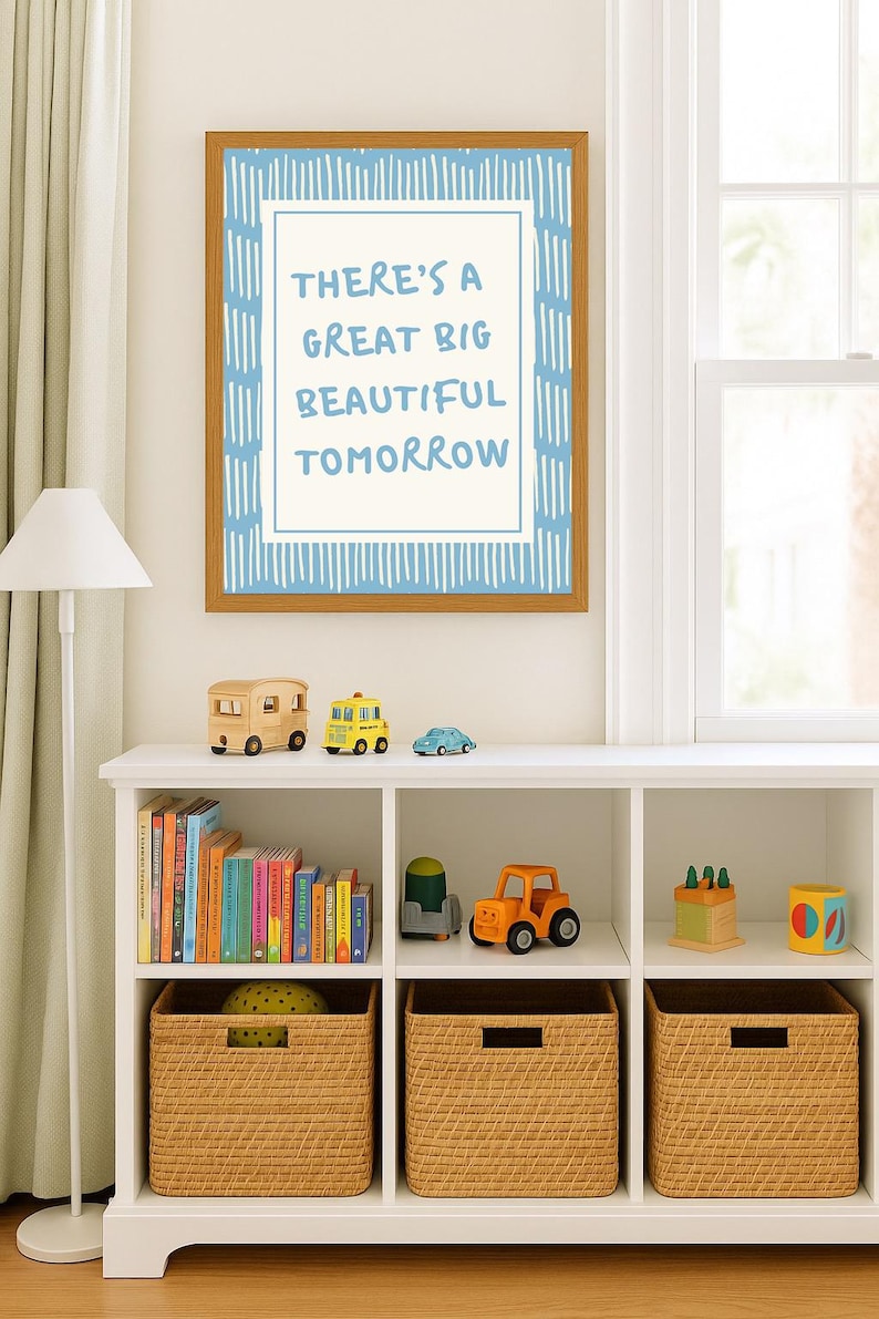 May include: A framed print with the text "THERE'S A GREAT BIG BEAUTIFUL TOMORROW" hangs above a white shelf. The shelf displays wooden toy vehicles, books, and woven storage baskets. The color scheme is light and airy.