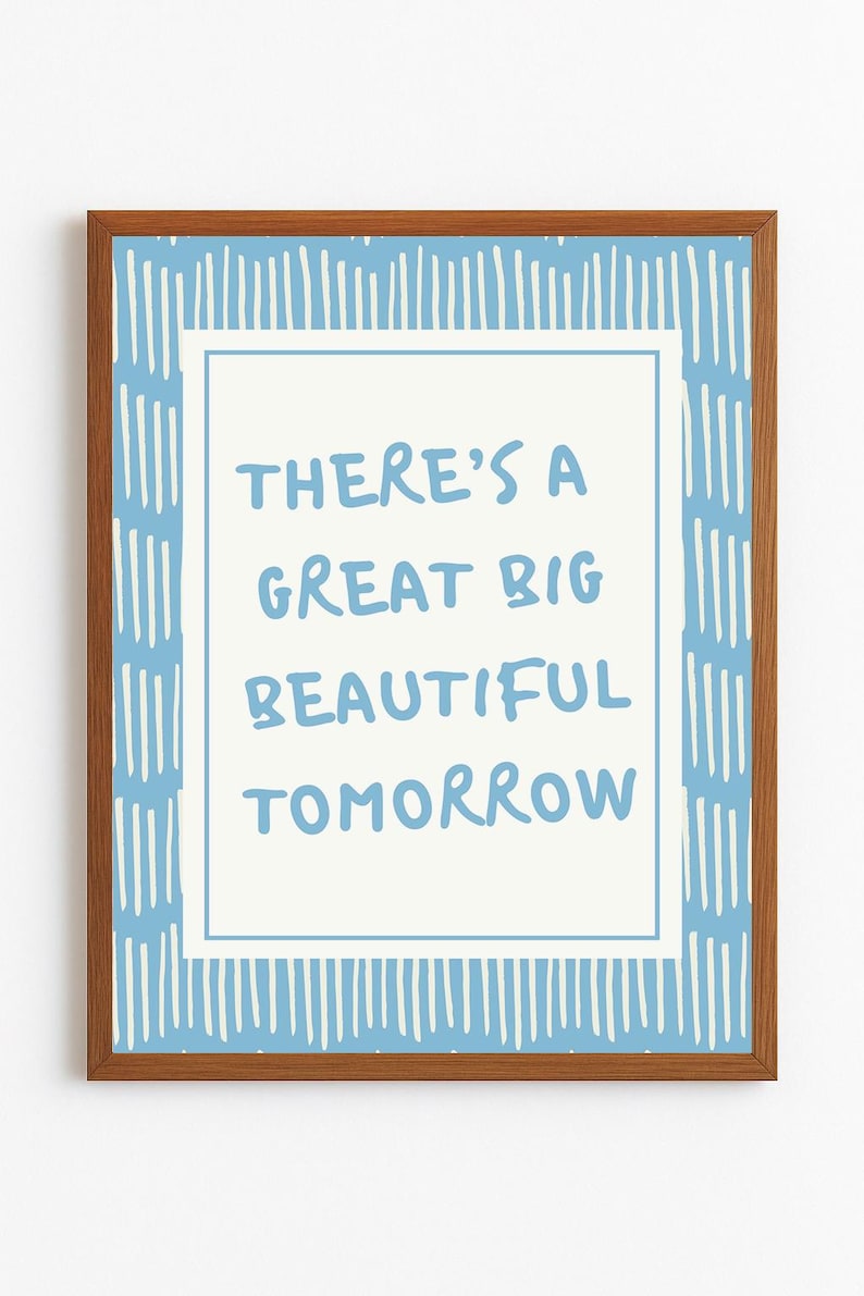 May include: A framed print with the words "THERE'S A GREAT BIG BEAUTIFUL TOMORROW" in light blue on a white background. The frame is brown, and the print has a blue and white striped border.