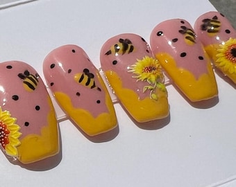 May include: Set of pink and yellow false nails with a bee and sunflower design.
