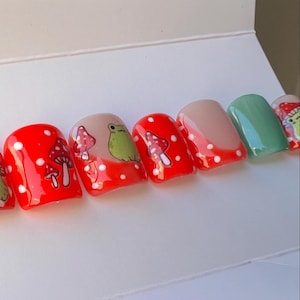 May include: Set of ten red and white polka dot press-on nails with mushroom and frog designs.