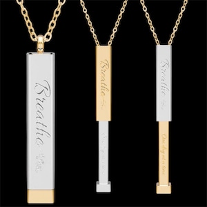 Könnte beinhalten: Drei goldfarbene Halsketten mit rechteckigen Anhängern. Jeder Anhänger trägt die Aufschrift "Breathe". Eine Halskette hat einen silberfarbenen Anhänger mit goldenem Sockel. Die anderen beiden haben goldfarbene Anhänger. Ein Anhänger trägt die Aufschrift "One day at a time".