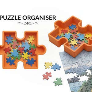 May include: Two orange puzzle-shaped organisers, each holding colourful puzzle pieces. The text "PUZZLE ORGANISER" is above the organisers. A partially assembled jigsaw puzzle is in the background.