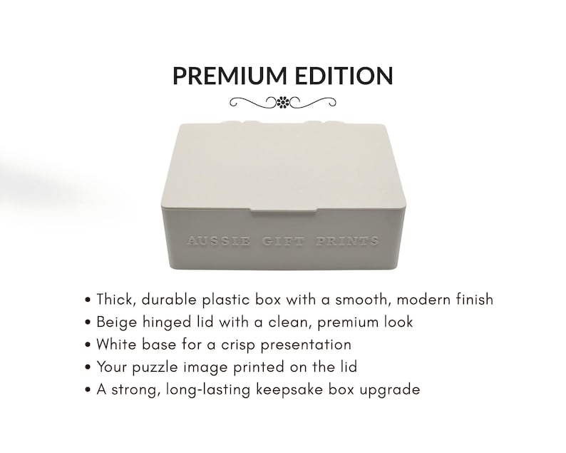 May include: A beige plastic box with a hinged lid, labeled "PREMIUM EDITION" and "AUSSIE GIFT PRINTS." The box has a white base and is designed for puzzles. The description highlights its durable construction and modern finish.