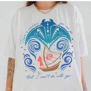 May include: White t-shirt featuring a colorful graphic design. The design includes a boat, waves, and a stylized palm tree in shades of blue, brown, and red. The text "There is nowhere you can go that I won't be with you..." is printed in blue.