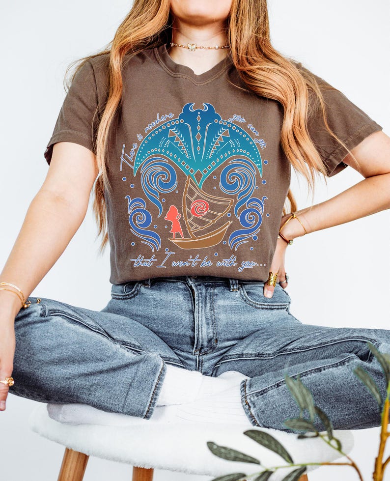 May include: Brown t-shirt featuring a graphic design with a boat, a figure, and swirling blue and teal elements. The text on the shirt reads "There is nowhere you are that I won't be with you..."
