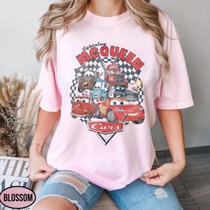 Puede incluir: Camiseta rosa claro con un estampado gr&aacute;fico de personajes de la pel&iacute;cula "Cars". El dise&ntilde;o incluye a Rayo McQueen, Mate y otros veh&iacute;culos, con las palabras "Lightning McQueen" y "Cars". La camiseta tiene un cuello redondo cl&aacute;sico.