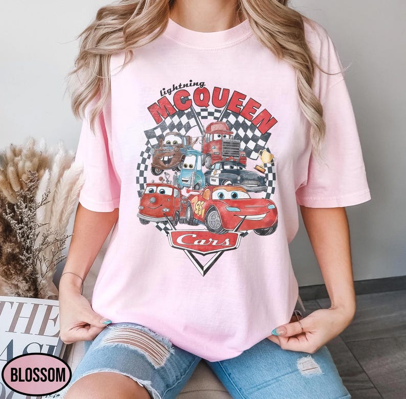 Puede incluir: Camiseta rosa claro con un estampado gr&aacute;fico de personajes de la pel&iacute;cula "Cars". El dise&ntilde;o incluye a Rayo McQueen, Mate y otros veh&iacute;culos, con las palabras "Lightning McQueen" y "Cars". La camiseta tiene un cuello redondo cl&aacute;sico.