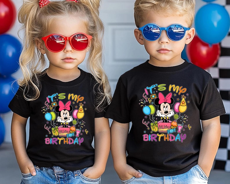 May include: Two children wearing black t-shirts with a Minnie Mouse birthday design. The shirts feature the text "It's my Birthday" with colorful graphics. One child wears red sunglasses, the other blue.