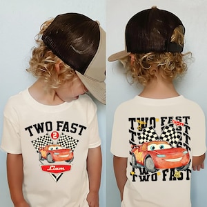 May include: A white ceramic mug with a black handle and the text "But First, Coffee" in a bold, black font. The mug is set against a blurred background, suggesting a cosy setting.