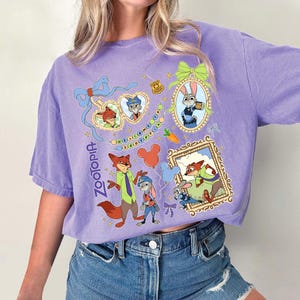 May include: A purple short-sleeved t-shirt featuring cartoon characters from the movie Zootopia. The shirt has multiple framed images of the characters, along with the word "Zootopia" in a script font.