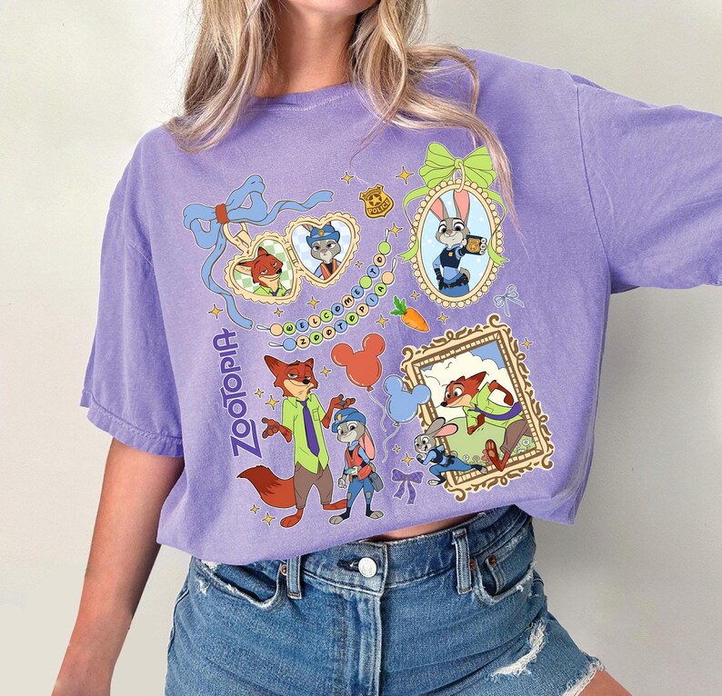May include: A purple short-sleeved t-shirt featuring cartoon characters from the movie Zootopia. The shirt has multiple framed images of the characters, along with the word "Zootopia" in a script font.