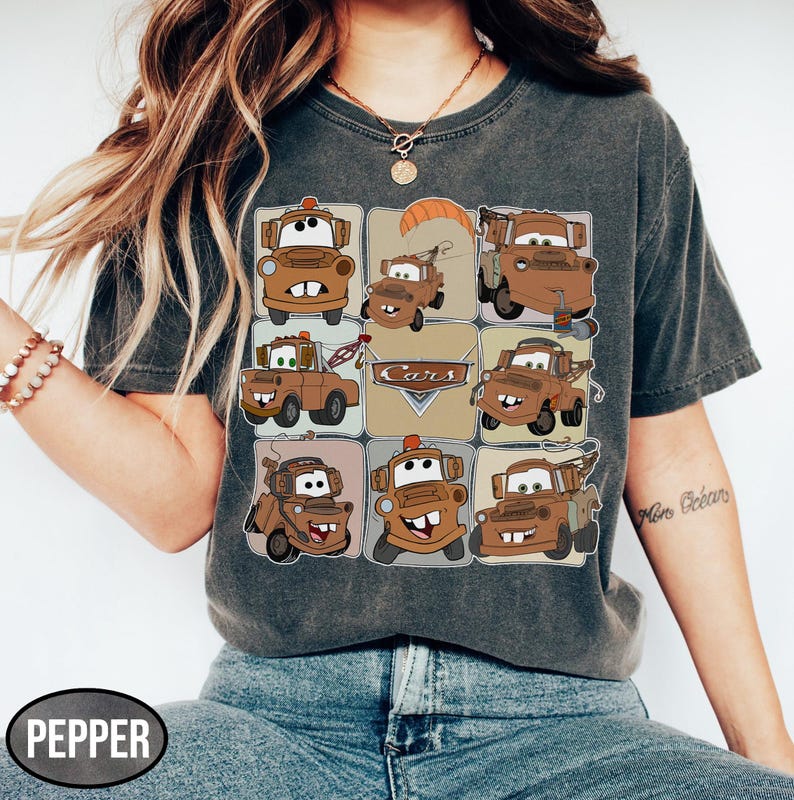 Może przedstawiać: Ciemnoszara koszulka z siatką brązowych kresk&oacute;wkowych w&oacute;zk&oacute;w holowniczych i napisem "Cars". Koszulka ma wygląd vintage, jest wyblakła i wykonana z miękkiego materiału.