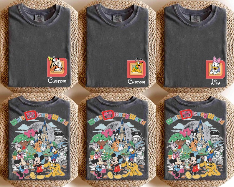May include: Six charcoal gray t-shirts. The top row features character designs with custom names. The bottom row displays a colorful graphic of Disney characters and the text "Walt Disney World". Each shirt is folded on a woven mat.