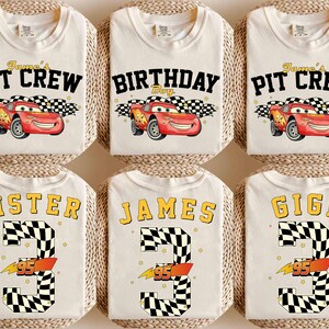 May include: Off-white t-shirts with various designs. Some shirts say "James' Pit Crew" with a red race car graphic. Others say "Birthday Boy", "Sister", "James", and "Gigi" with a number 3 and the number 95.