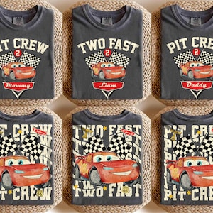 May include: A white ceramic mug with a black handle and the text "But First, Coffee" in a bold, black font. The mug is set against a blurred background. The mug appears to be approximately 10 cm tall.