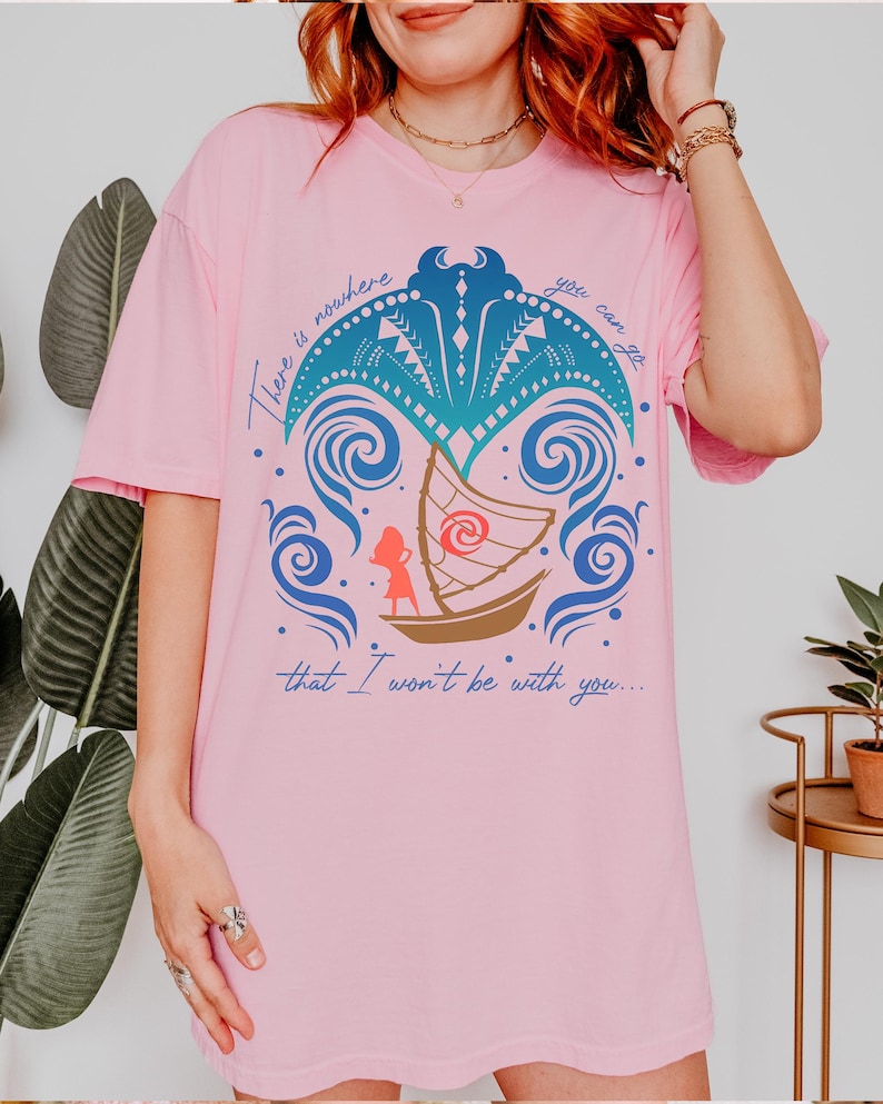 May include: Pink t-shirt featuring a graphic design with a boat, waves, and palm tree elements. The design includes the text "There is nowhere you can go that I won't be with you..."