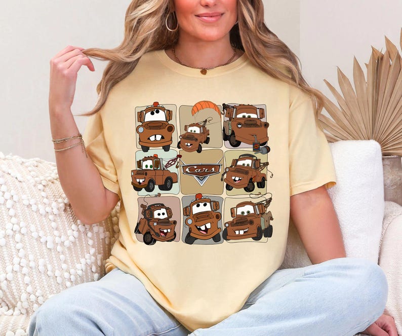 Może przedstawiać: Jasnoż&oacute;łta koszulka z siatką dziewięciu kresk&oacute;wkowych obraz&oacute;w postaci Złomka z filmu Auta. Obrazy są w odcieniach brązu i beżu, ze słowem "Cars" pośrodku.