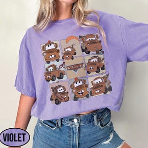 Może przedstawiać: Fioletowa koszulka z siatką brązowych kresk&oacute;wkowych w&oacute;zk&oacute;w holowniczych. Słowo "Cars" jest nadrukowane na wzorze. Koszulka ma kr&oacute;tkie rękawy i luźny kr&oacute;j. Słowo "VIOLET" jest wydrukowane po lewej stronie u dołu.